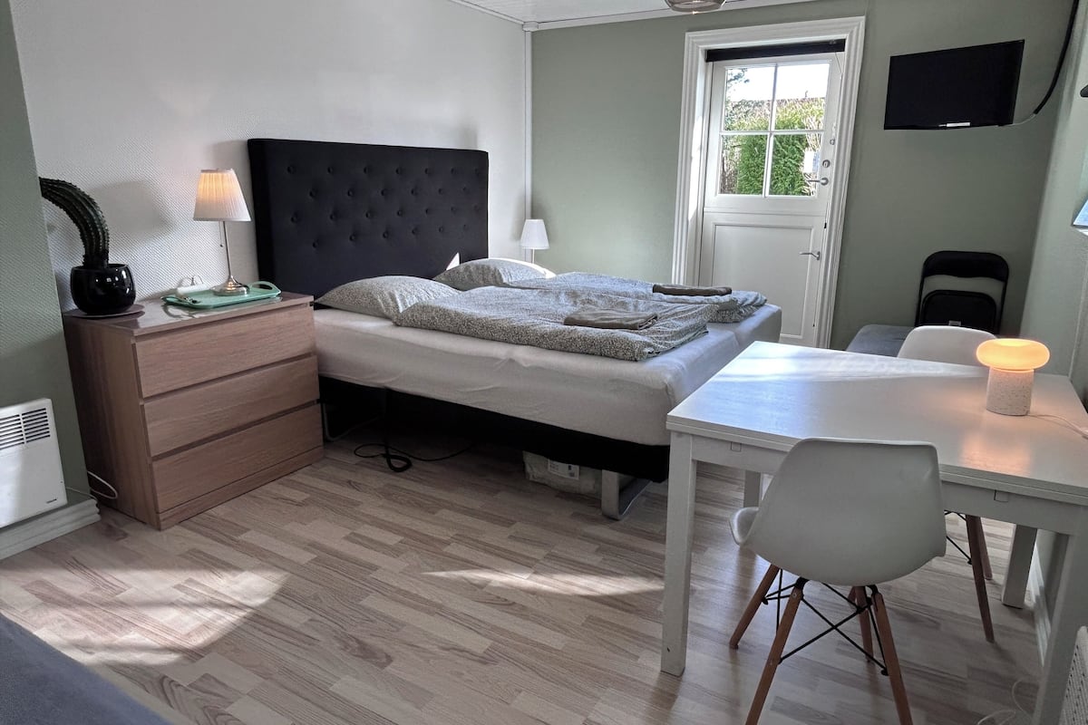 A bedroom with a bed, bedside tables, a desk, and a chair.