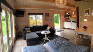 A cozy room with a sofa, a small table, and a kitchen area with cabinets and a microwave. - Piccobello Bed & Breakfast (Koge)