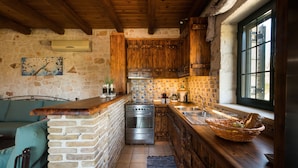 Una cocina compacta con pared de piedra, armarios de madera, horno empotrado y un ventanal amplio.