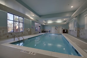 Una piscina interior con agua cristalina, marcas de profundidad y un cartel de prohibido bucear.