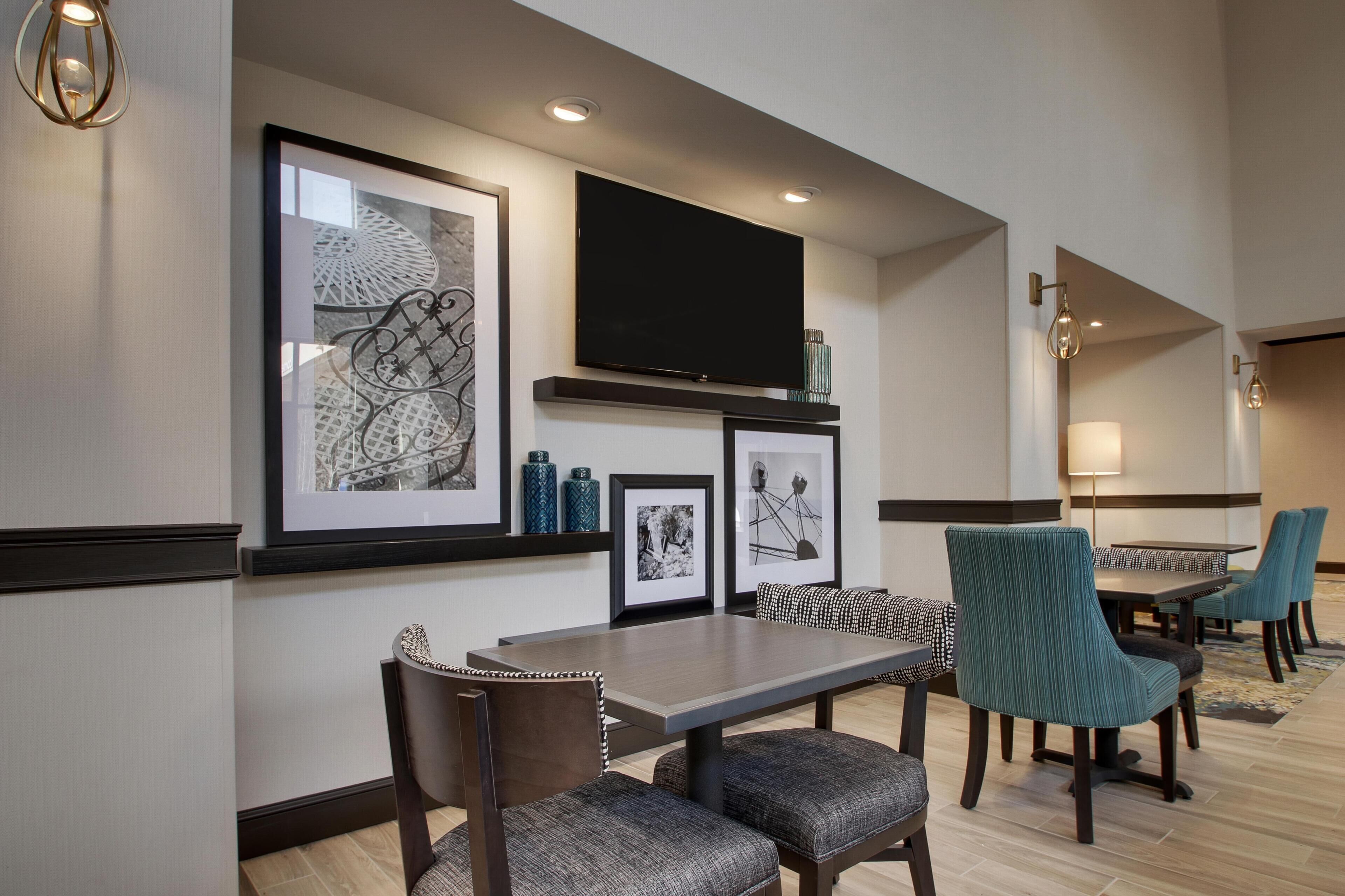 A hotel dining area with a long table, chairs, and artwork on the walls.