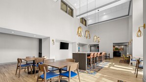 Amplio espacio interior con diversas disposiciones de asientos, incluidas mesas y sillas, y una zona de bar central.