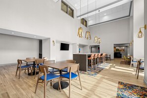 A spacious indoor area with multiple seating arrangements, including tables and chairs, and a central bar area. - Hampton Inn & Suites Knightdale Raleigh (Raleigh)