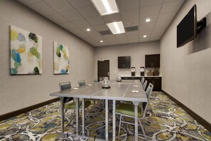 A conference room with a long table, chairs, a flat-screen TV, artwork on the walls, and a patterned carpet. - Hampton Inn & Suites Knightdale Raleigh (Raleigh)