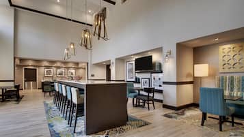 A hotel lobby with a bar area, seating, and artwork on the walls.