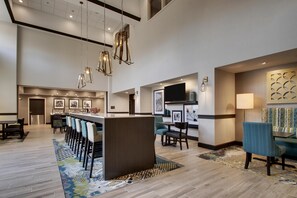 A hotel lobby with a bar area, seating, and artwork on the walls. - Hampton Inn & Suites Knightdale Raleigh (Raleigh)