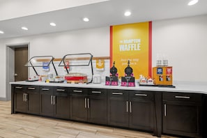 A breakfast bar with waffle makers and a sign for The Hampton Waffle. - Hampton Inn & Suites Knightdale Raleigh (Raleigh)