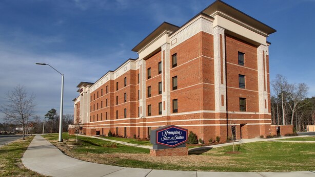Un edificio grande de ladrillo con un letrero que dice "Hampton Inn & Suites by Hilton".