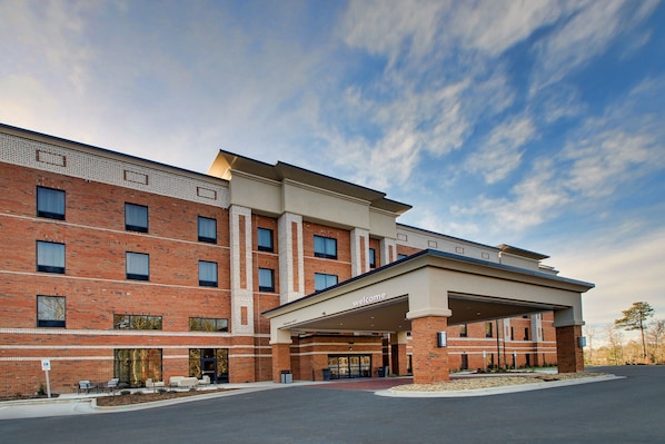 A multi-story hotel with a brick facade, a covered entrance, and a clear sky. - Hampton Inn & Suites Knightdale Raleigh (Raleigh)