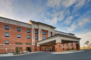 A multi-story hotel with a brick facade, a covered entrance, and a clear sky. - Hampton Inn & Suites Knightdale Raleigh (Raleigh)