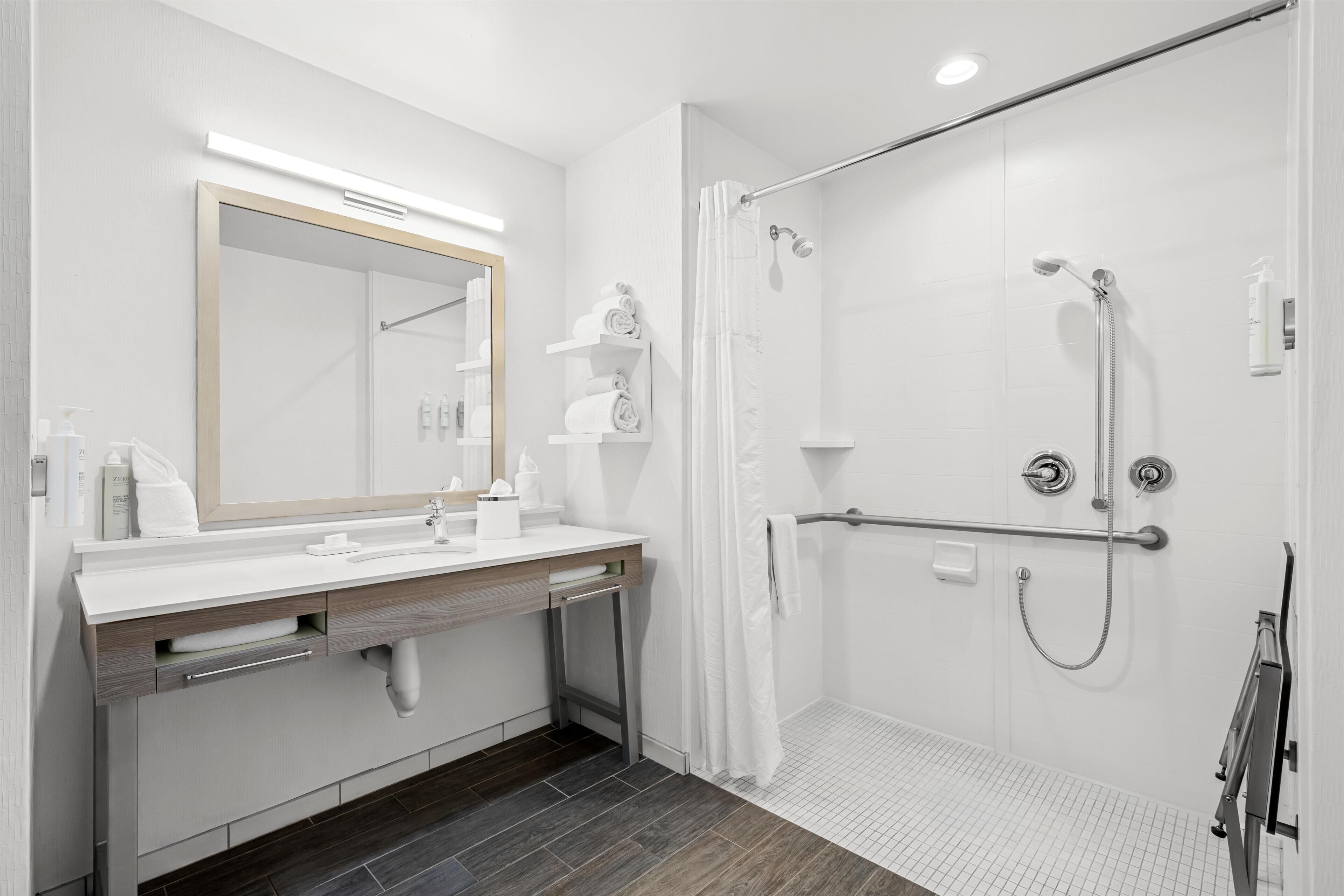 A modern bathroom with a shower, a vanity with a mirror, and a toilet.