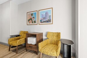 A hotel room with two patterned chairs, a small table, a printer, and two framed pictures on the wall. - Hampton Inn & Suites Knightdale Raleigh (Raleigh)