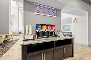 A modern kitchen area with a coffee station featuring four coffee dispensers labeled 'DARK ROAST,' 'LIGHT ROAST,' 'DECAF ROAST,' and 'HOT WATER.' - Hampton Inn & Suites Knightdale Raleigh (Raleigh)