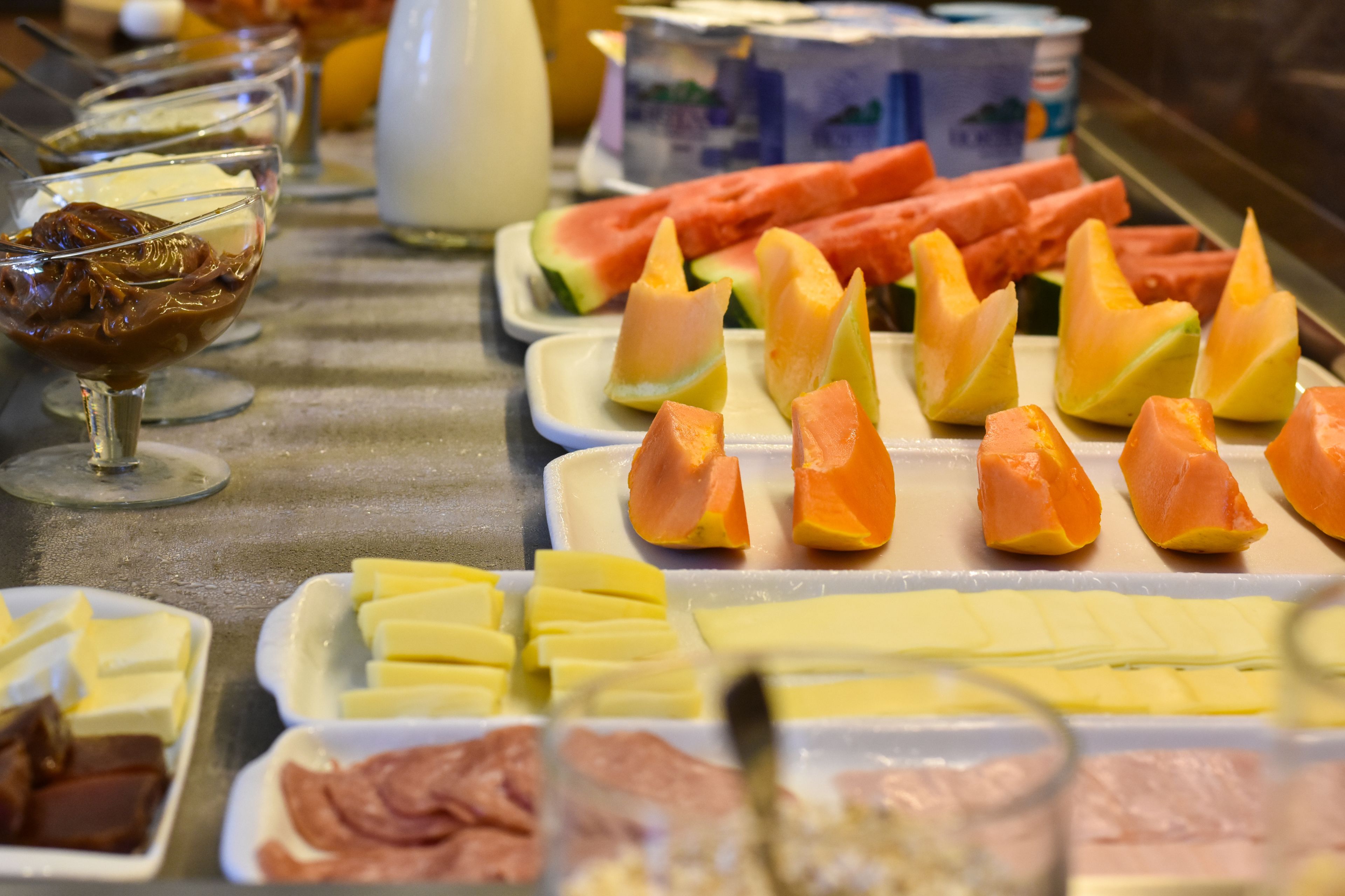 A buffet with various food items including fruits, cheeses, and meats.