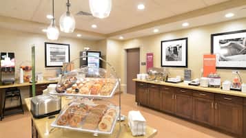 A breakfast buffet area with various food items, a coffee station, and a counter with kitchen appliances.