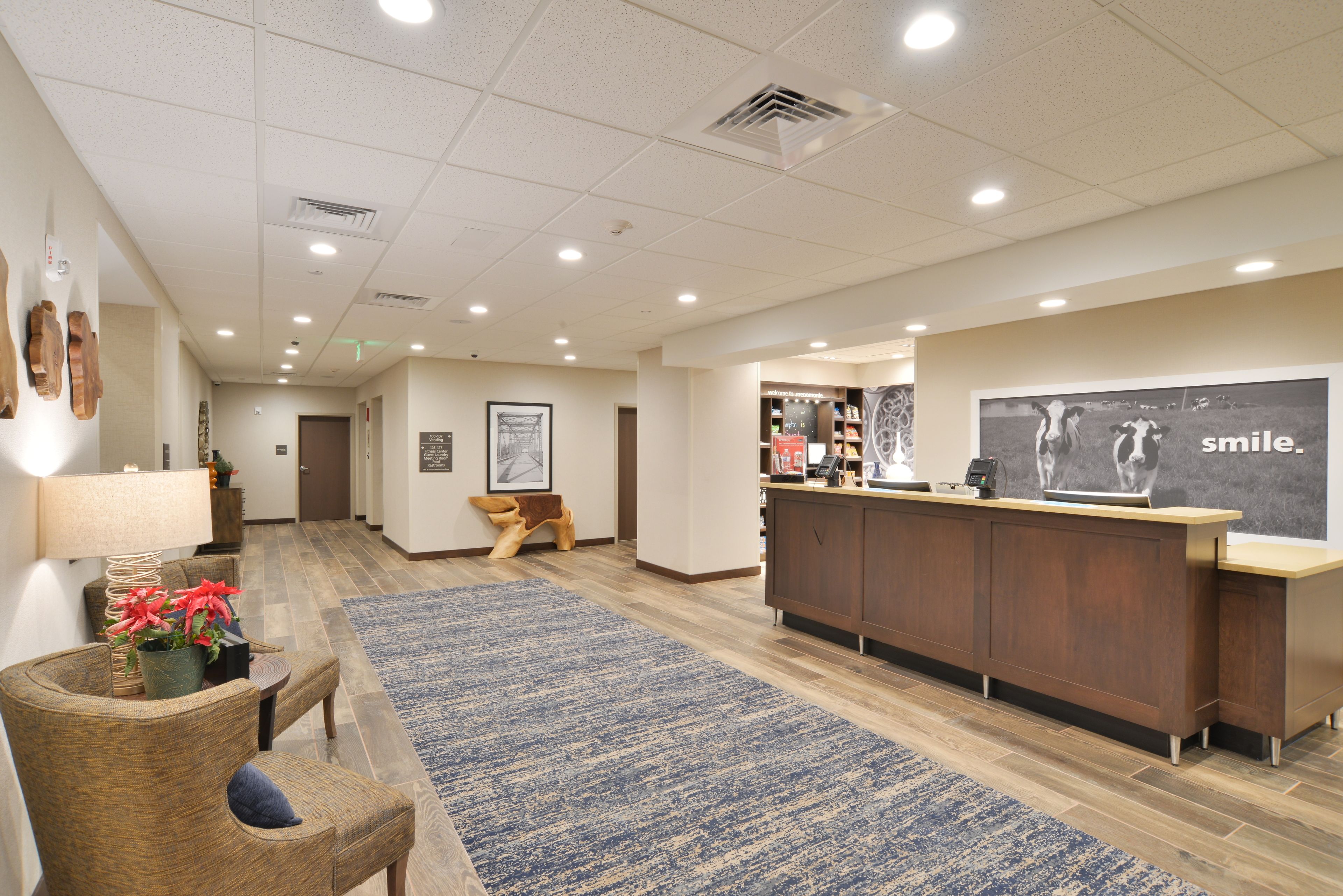 A reception area with a wooden reception desk, a blue patterned rug, and a wall with a 'smile' poster.