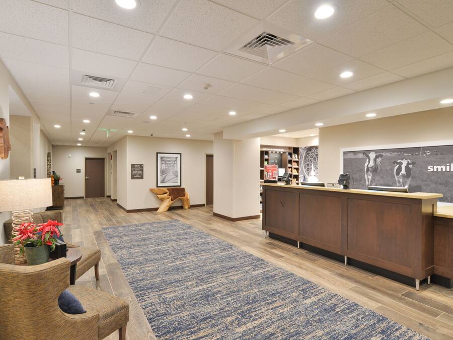 A reception area with a wooden reception desk, a blue patterned rug, and a wall with a 'smile' poster.