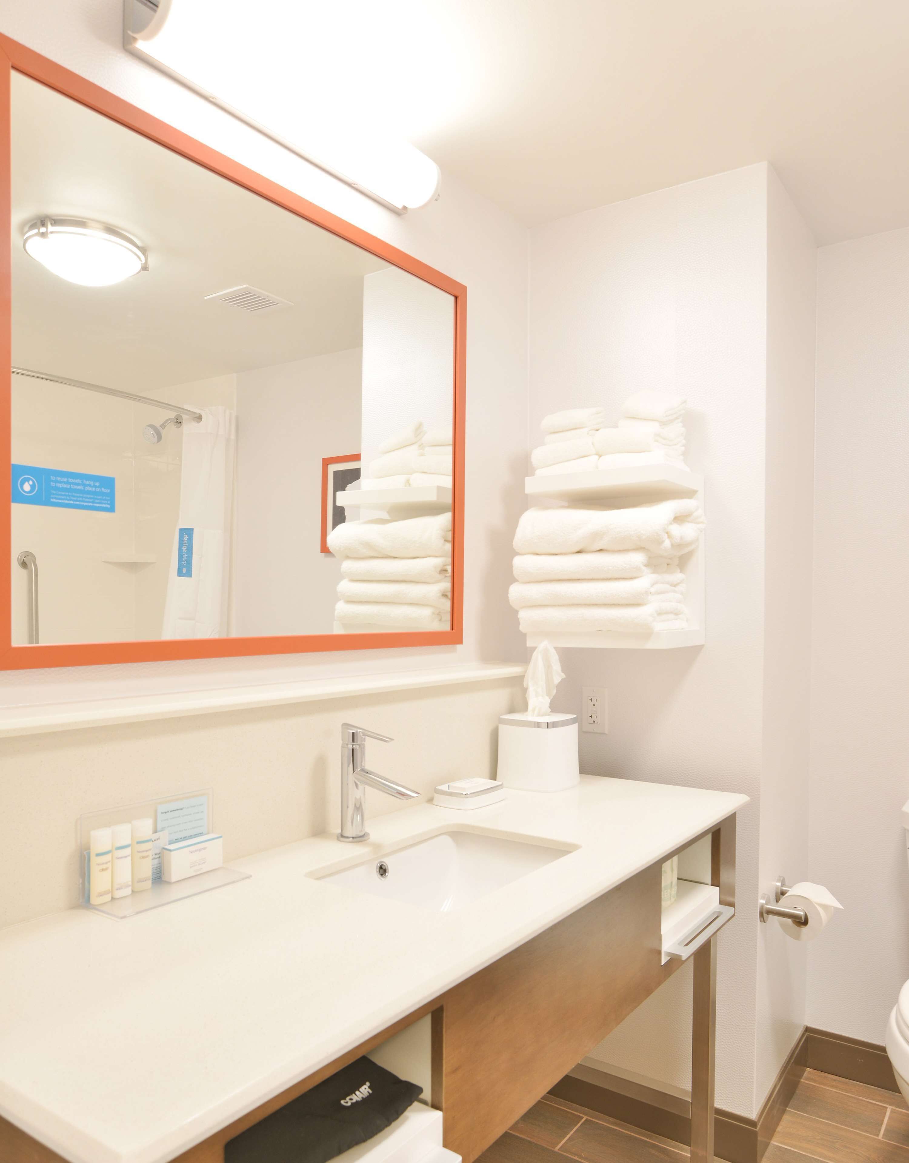 Een hotelbadkamer met een grote spiegel, een wastafel, een handdoekhouder en een toilet.