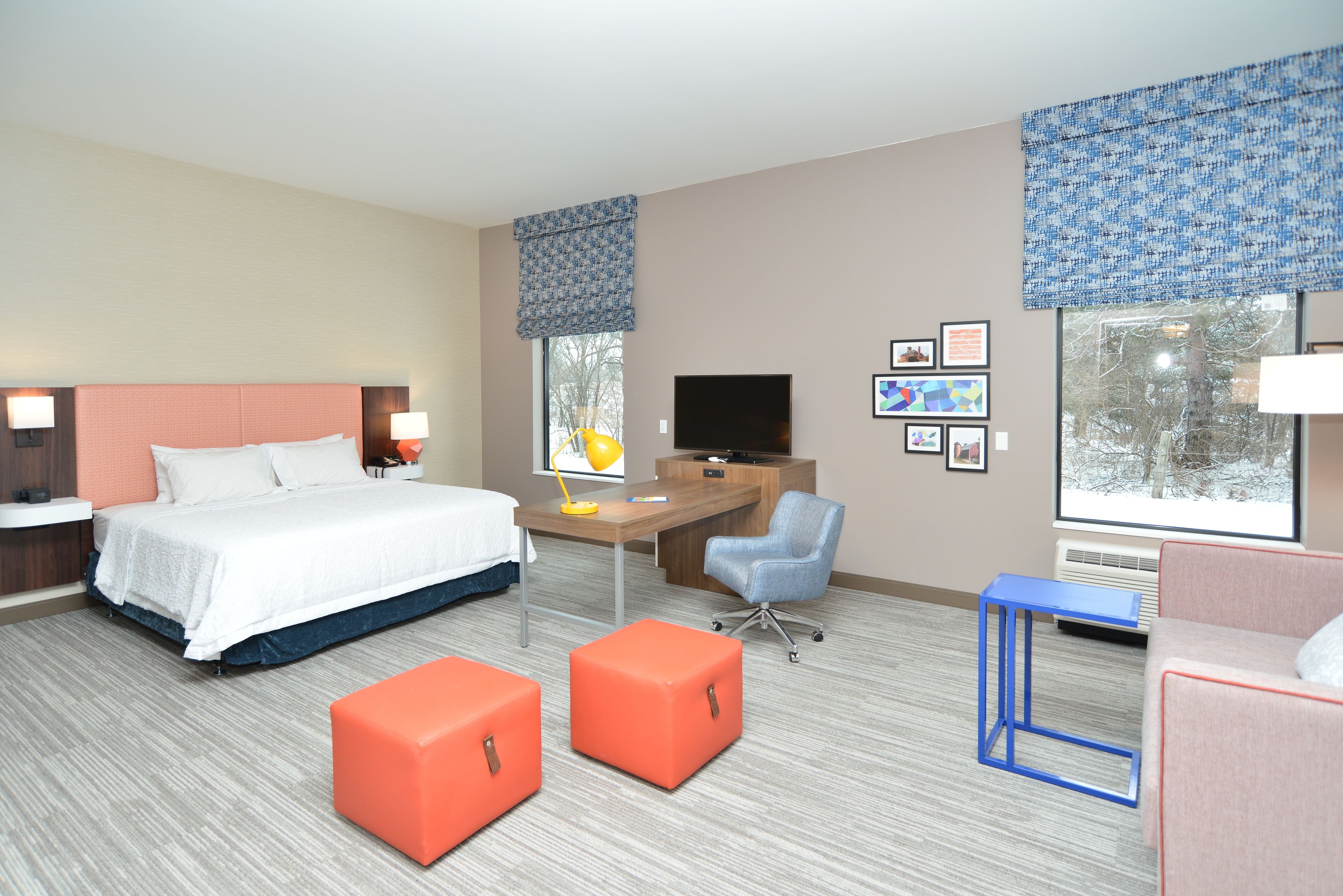 Habitación de hotel con cama, escritorio, ordenador y zona de estar.