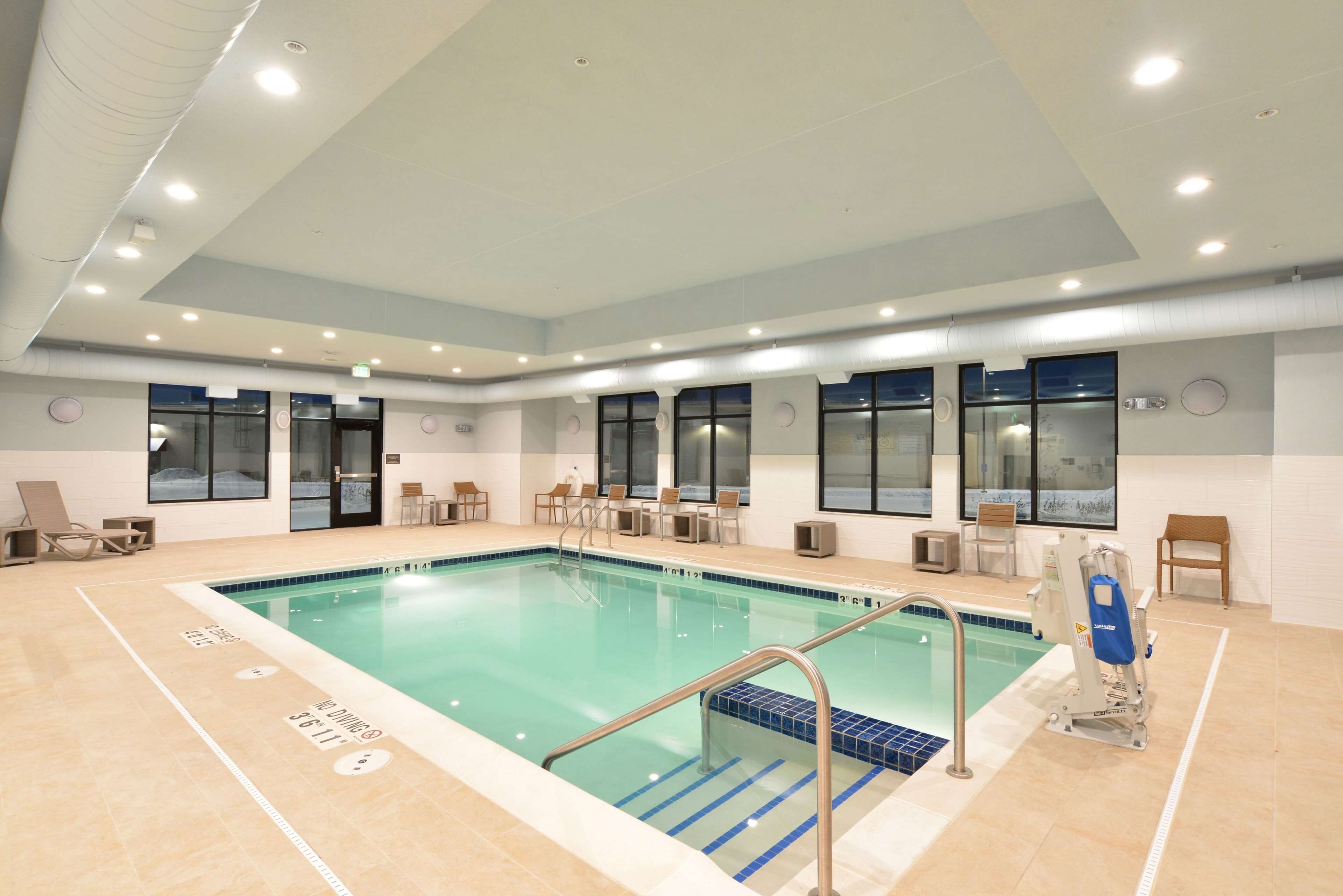 A swimming pool with a tiled deck, lounge chairs, and a lifeguard chair.