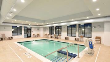A swimming pool with a tiled deck, lounge chairs, and a lifeguard chair.
