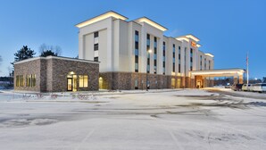 A modern hotel with a stone facade, multiple floors, and a well-lit entrance.