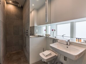 A modern bathroom with a shower, toilet, and sink.