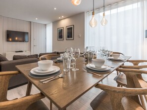 Un espace repas moderne avec une table en bois, dressée pour quatre personnes, entourée de chaises en bois.