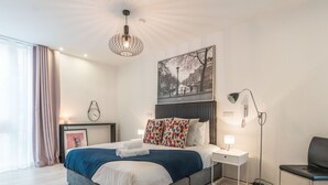 Quarto de hotel moderno com uma cama grande, mesas de cabeceira, escrivaninha e uma cadeira.