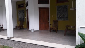 A covered porch with two wooden doors, a white pillar, and a tiled floor. - Rooms One Five Four (Seeduwa - Katunayake)
