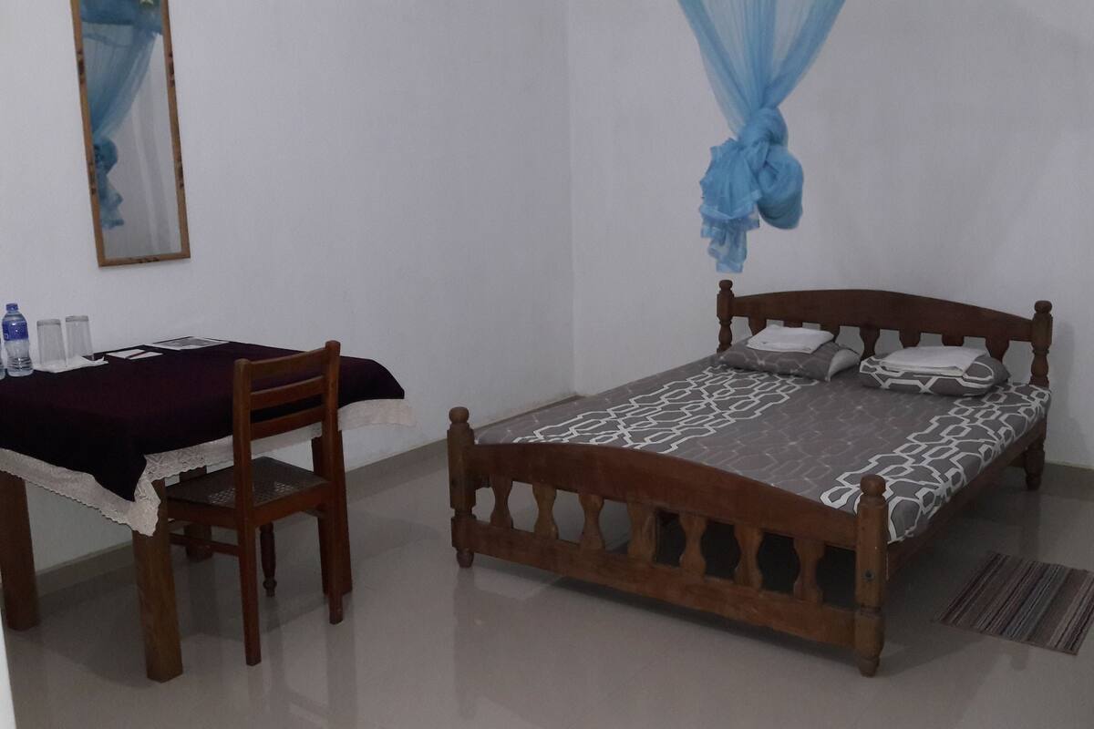 Ein Schlafzimmer mit einem hölzernen Bett, einem Nachttisch, einem Stuhl und einem Deckenventilator.