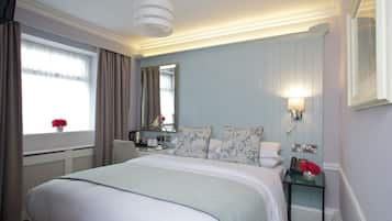 Una habitación de hotel con una cama grande, una mesita de noche, un espejo y una ventana con cortinas.