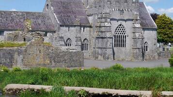 A historic stone building with a large arched window and a tower.