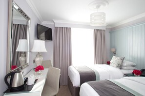 A hotel room with a bed, a desk with a lamp, a mirror, a television, and a view of the outdoors. - Hayes Hotel (Thurles)