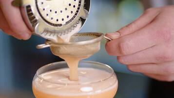A person pouring a drink into a martini glass.