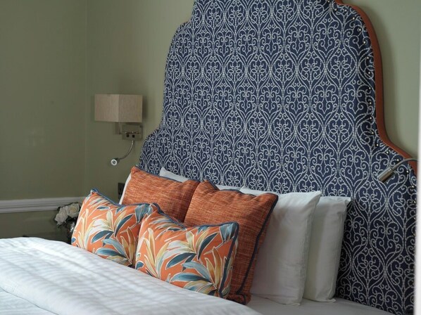 A bed with a patterned headboard, a nightstand with a lamp, and decorative pillows. - Hayes Hotel (Thurles)