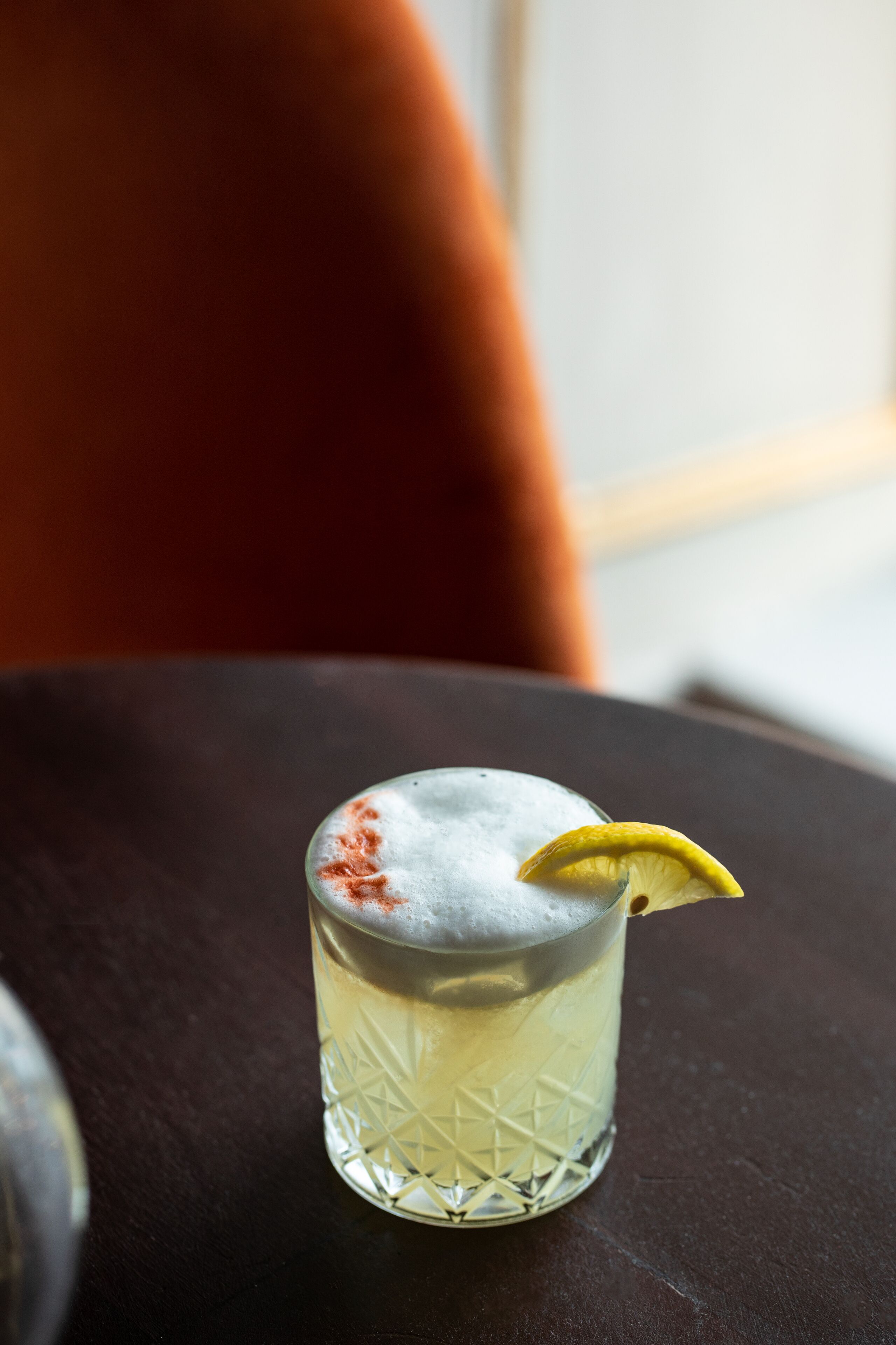 Un verre contenant une boisson claire, décorée d’une tranche de citron, posé sur une surface sombre.