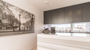 A modern kitchen with a marble countertop, dark cabinets, and a cityscape view through large windows. - The John Fitzgerald Kennedy Suite - hiphipstay (Dublin)