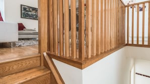 Una escalera de madera con una pared blanca y un cuadro de fondo.