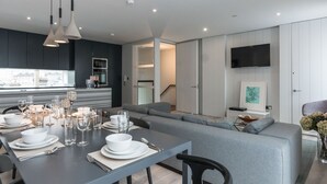 A modern living room with a dining area, grey sofas, and a flat-screen TV mounted on the wall. - The Michael Collins Suite - hiphipstay (Dublin)