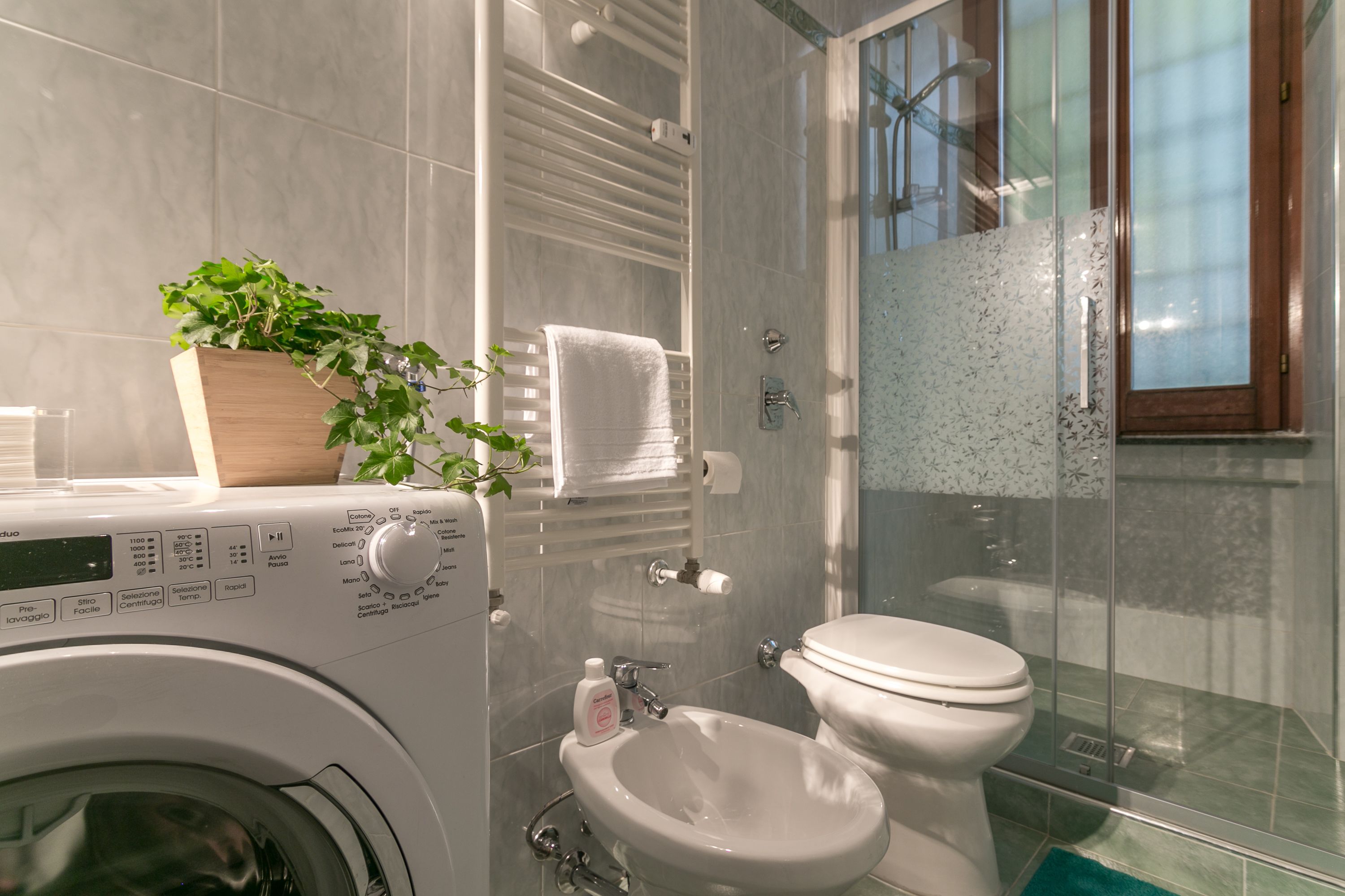 A modern bathroom with a washing machine, a sink, and a toilet.