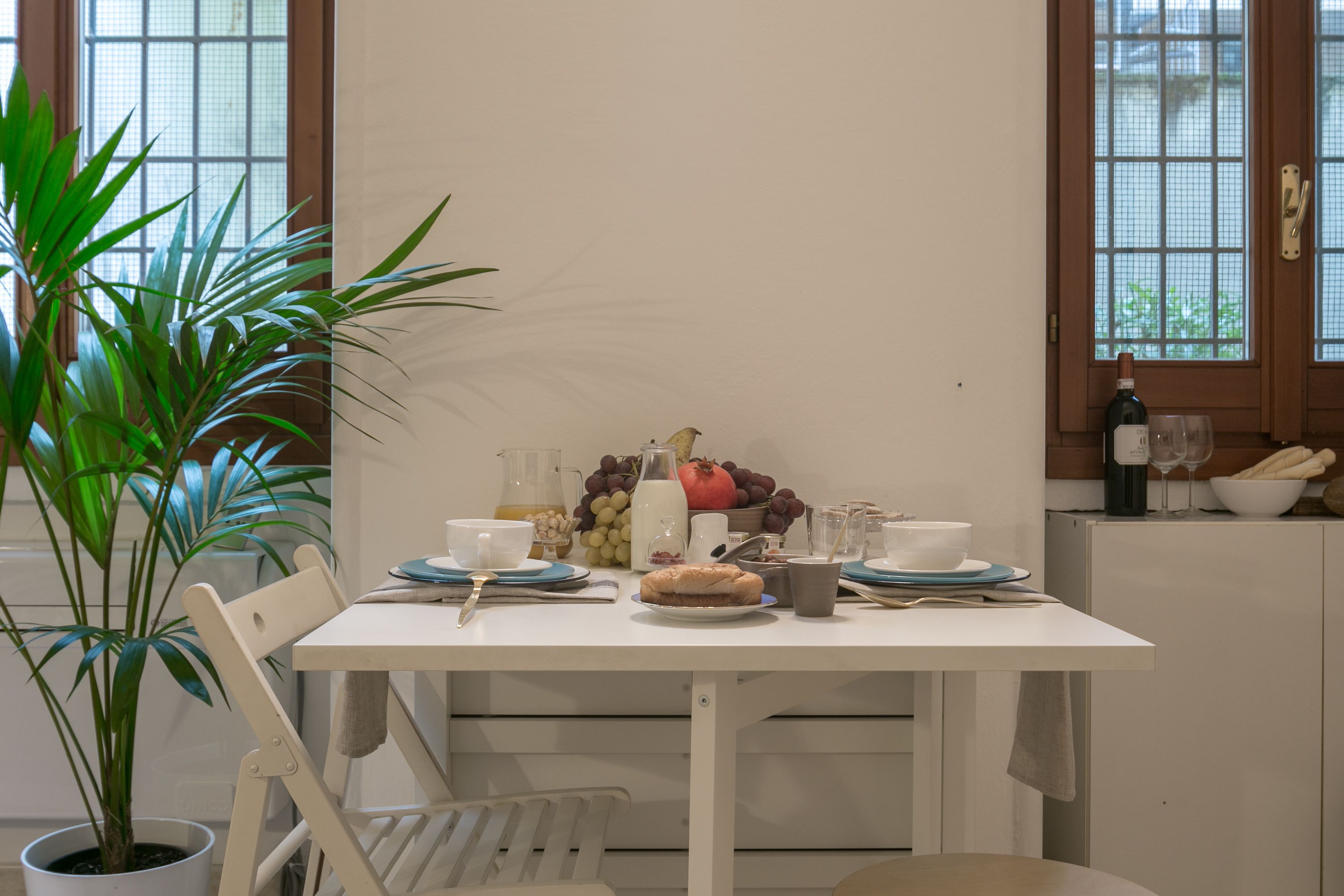 A dining table set with plates, cups, and a pitcher of juice, surrounded by chairs.
