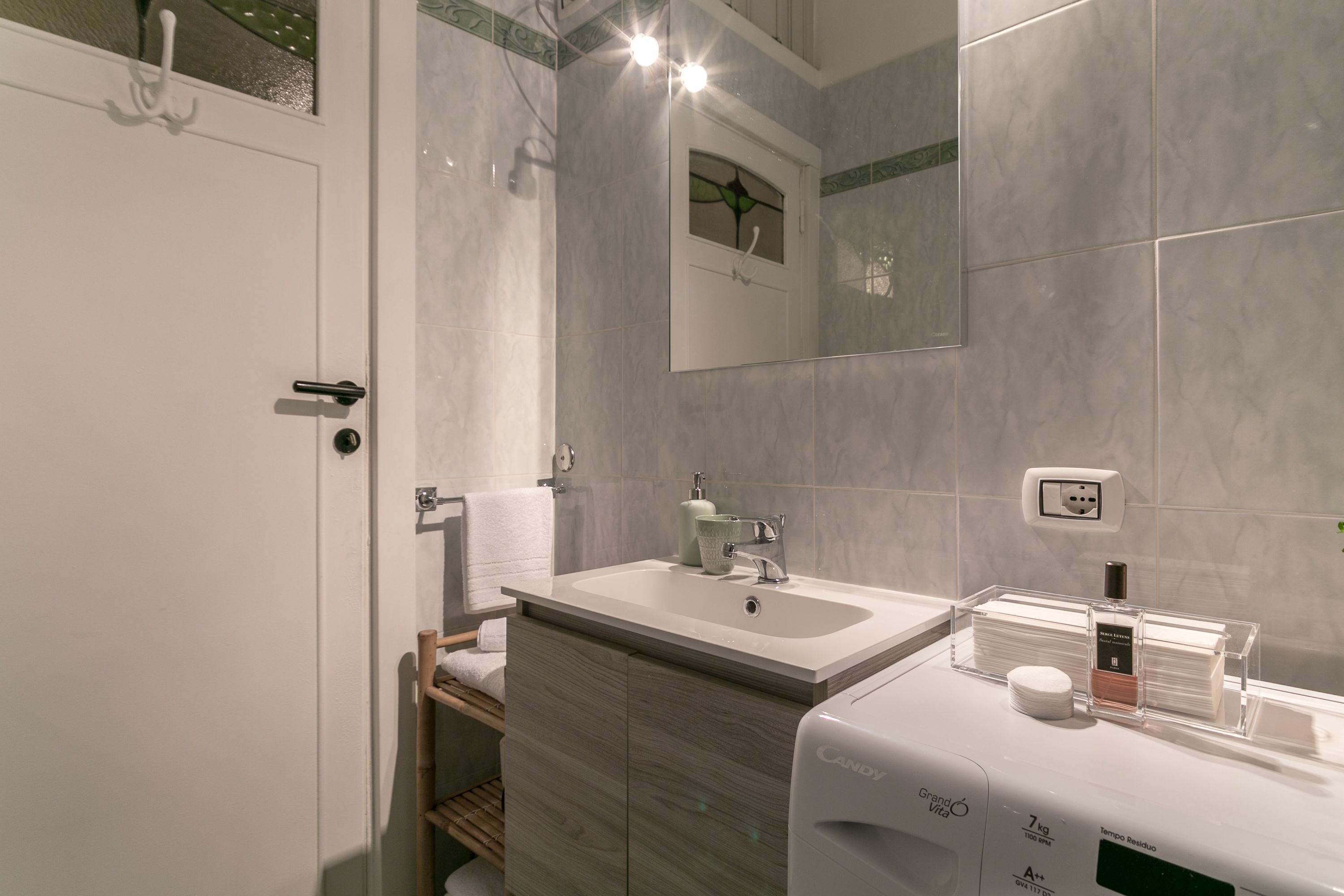 A modern bathroom with a white sink, mirror, and a soap dispenser on the counter.
