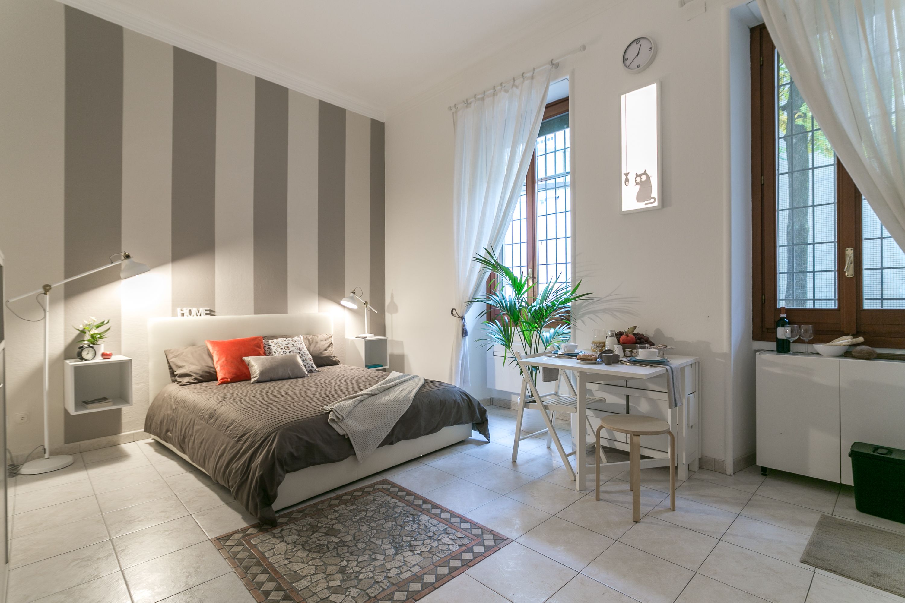 Een slaapkamer met een bed, nachtkastje, lamp en een kleine plant.