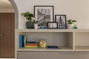 A bookshelf with books, a jar of lemons, and framed pictures. - notaMi -  Next Stop - Central Station (Milan)