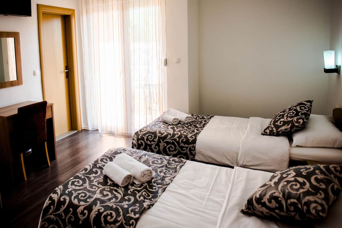 A hotel room with two beds, a desk, and a chair.