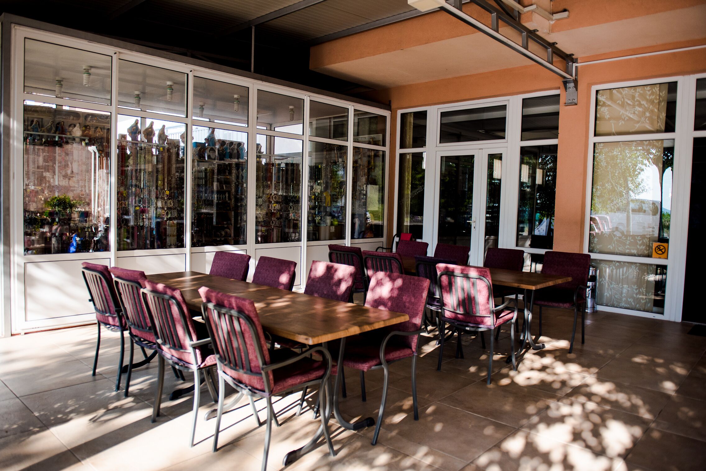 A restaurant with large windows, a wooden table, and red chairs.