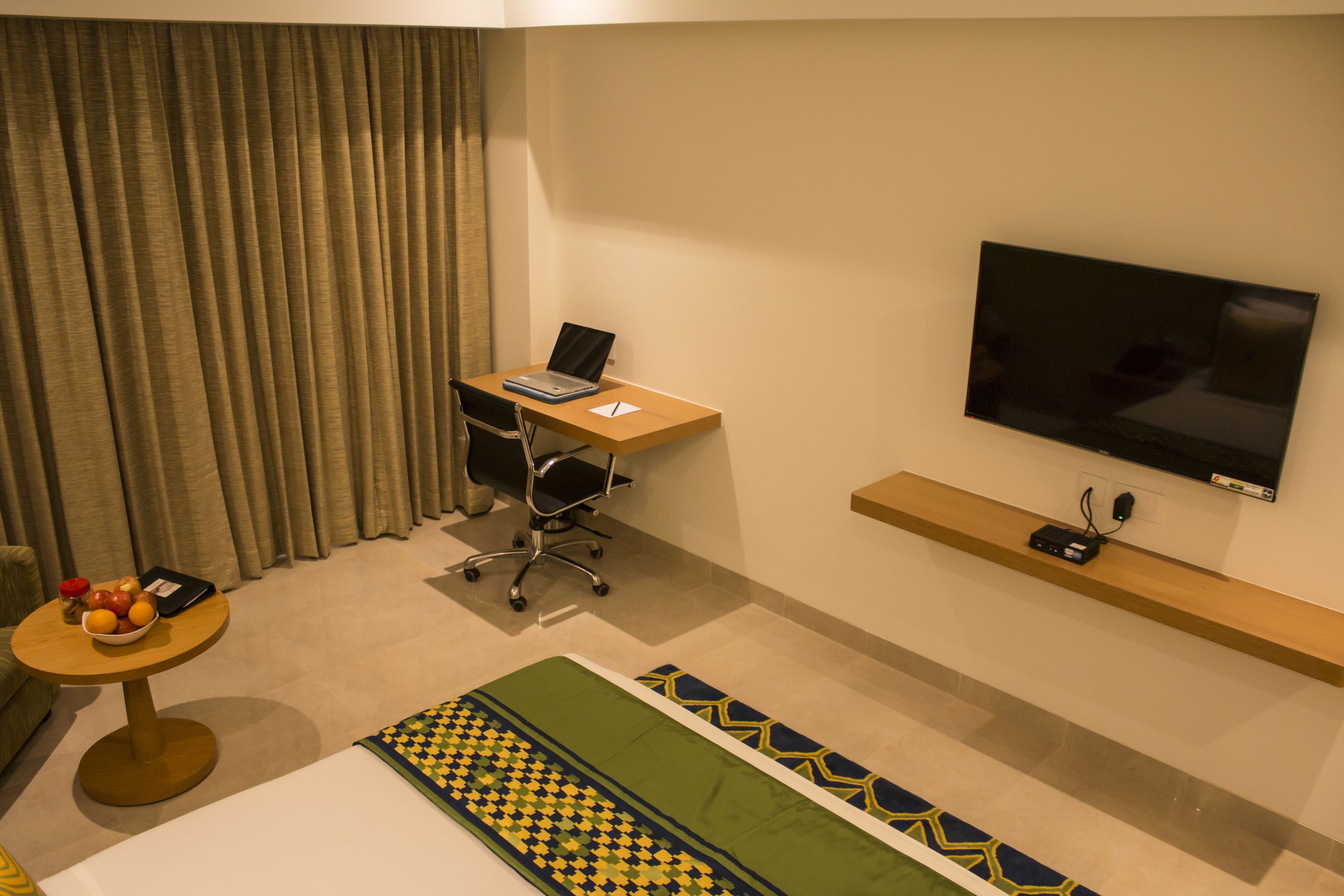 Habitación de hotel con escritorio, silla, televisor y cama.