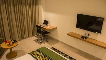 Habitación de hotel con escritorio, silla, televisor y cama.