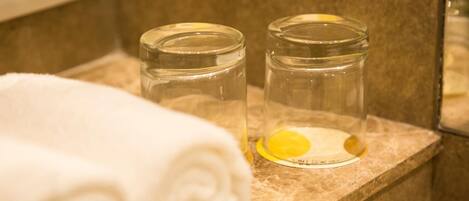 Deux pots en verre contenant une substance jaune sont posés sur le comptoir d’une salle de bain.